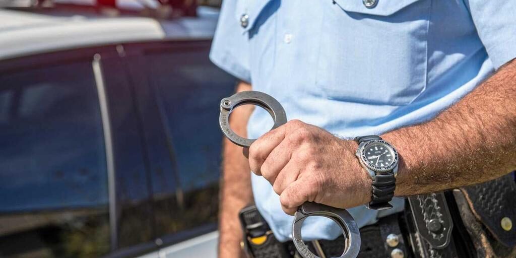 police officer holding handcuffs for criminal