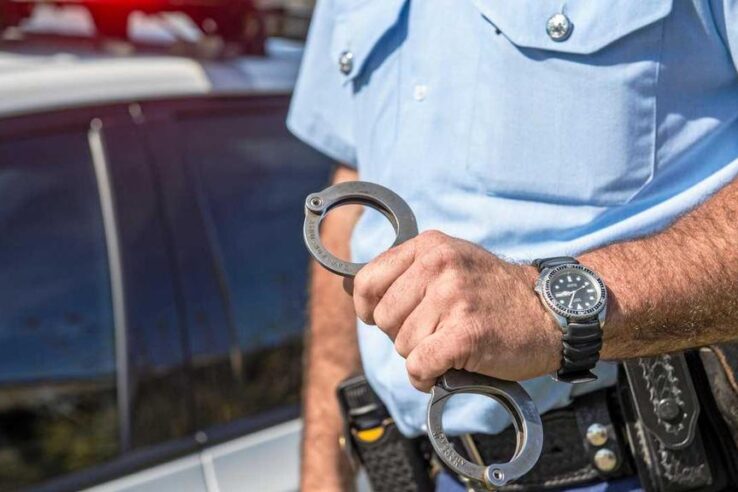 police officer holding handcuffs for criminal