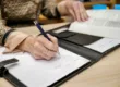A hand with a pen, writing notes on paper.