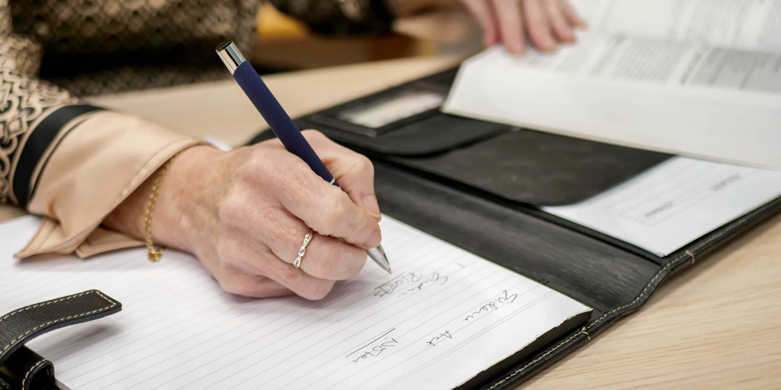A hand with a pen, writing notes on paper.