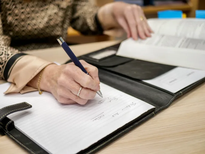Writing with Pen A hand with a pen, writing notes on paper.
