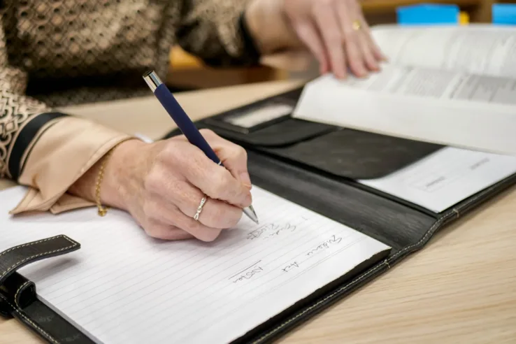 A hand with a pen, writing notes on paper.